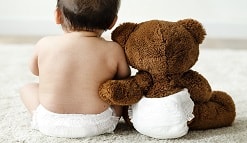Baby and teddy bear in diapers.